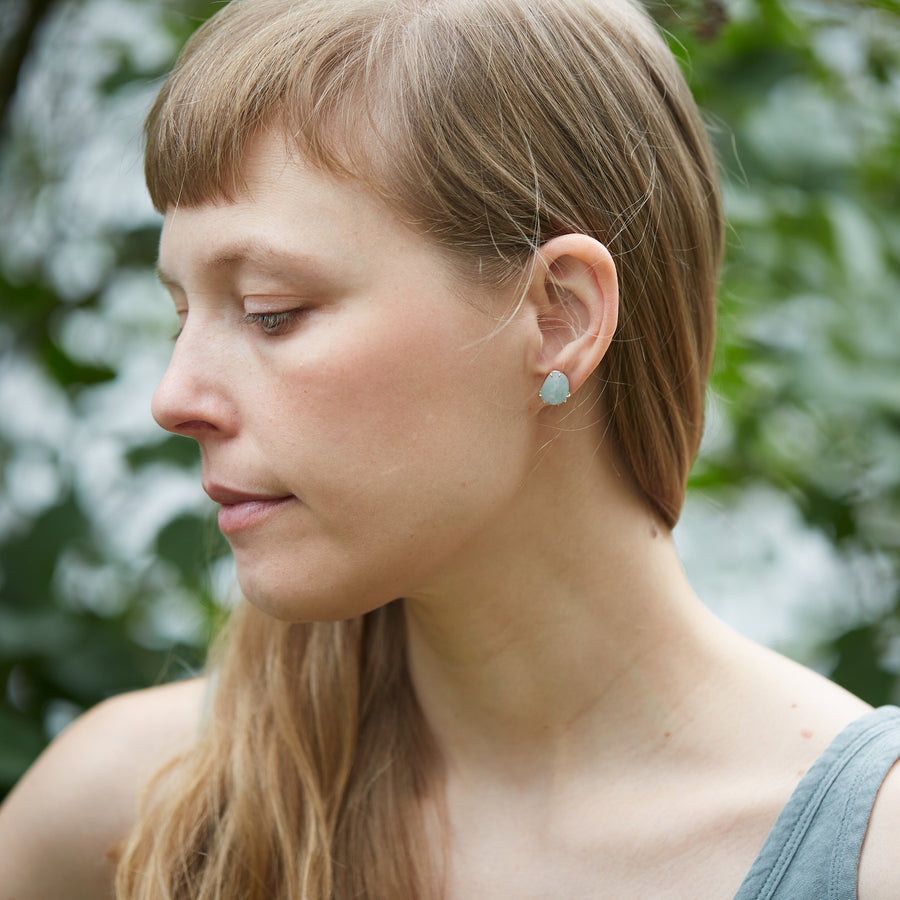 pale grey blue aquamarine stones with gold prongs. stud earrings on person.