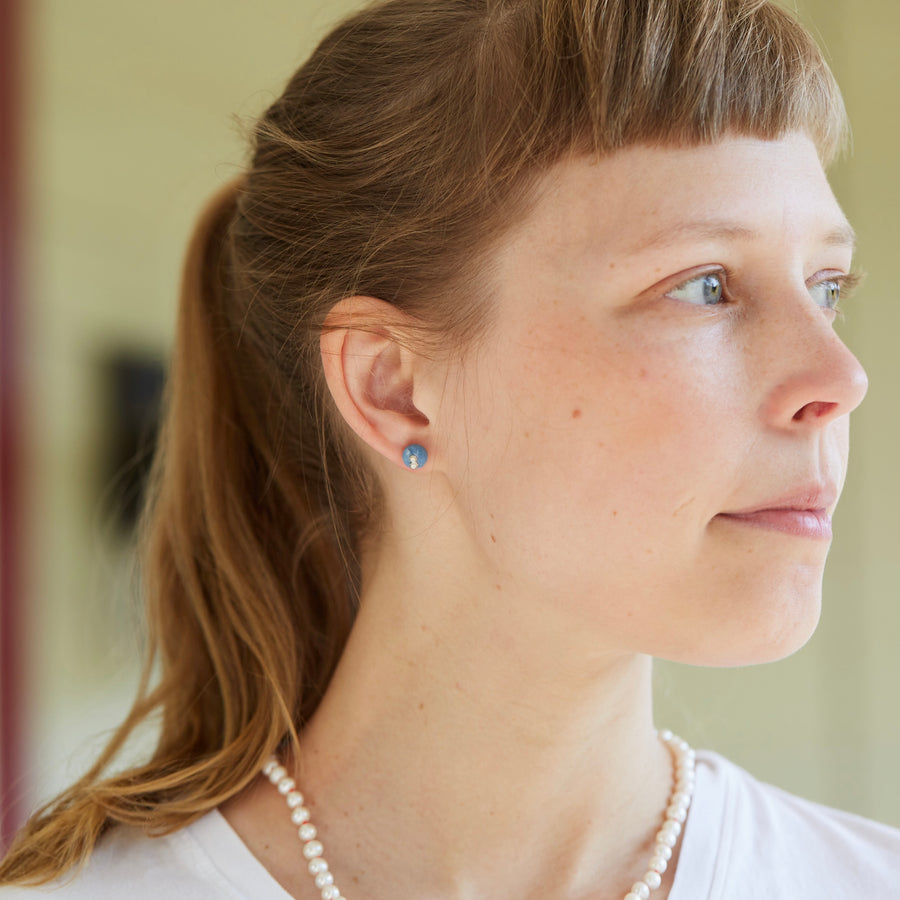 blue common opal earring studs with silver barnacles on person