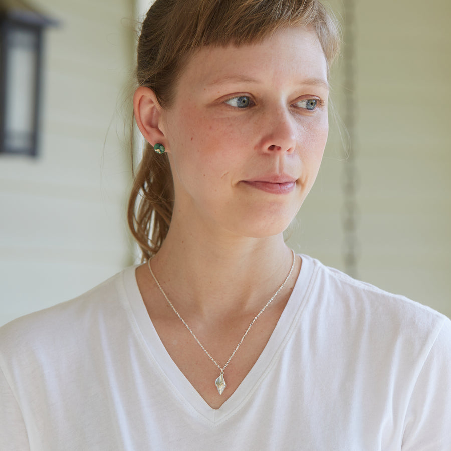 silver spiral tulip shell with two gold barnacles with diamonds, on a silver chain, on person